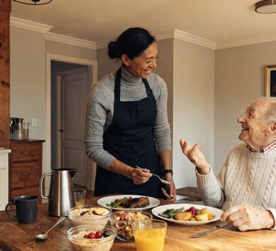 Professional caregiver assisting an elderly person with a nutritious meal